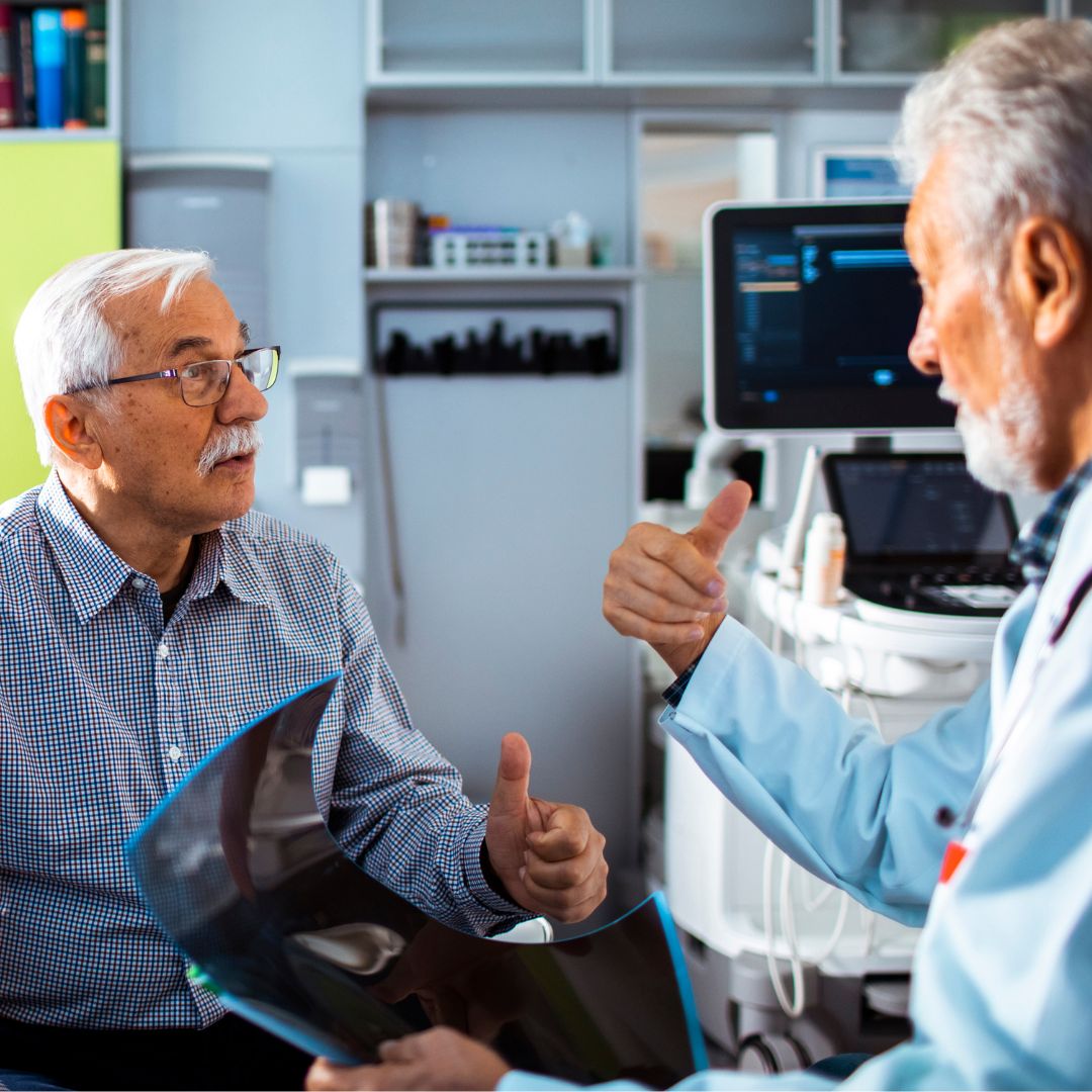 Elder man listening as his doctor explains an x-ray in his hand